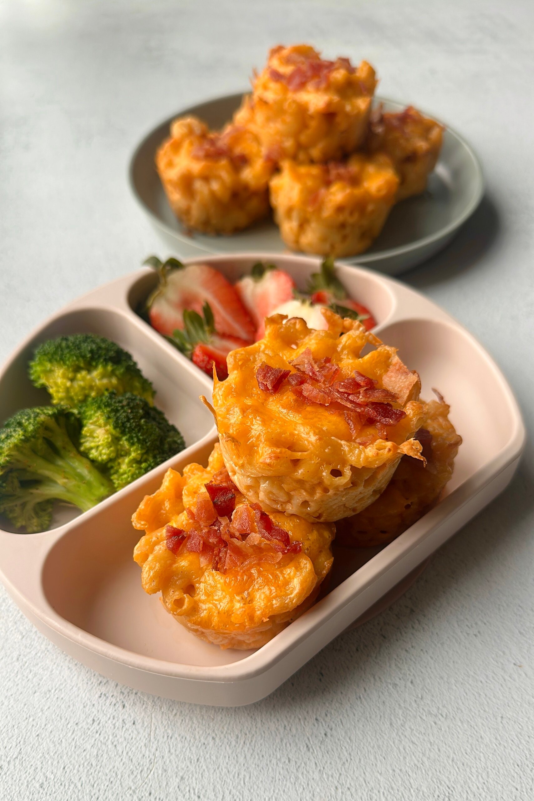 Mac and cheese muffins served with strawberries and broccoli.