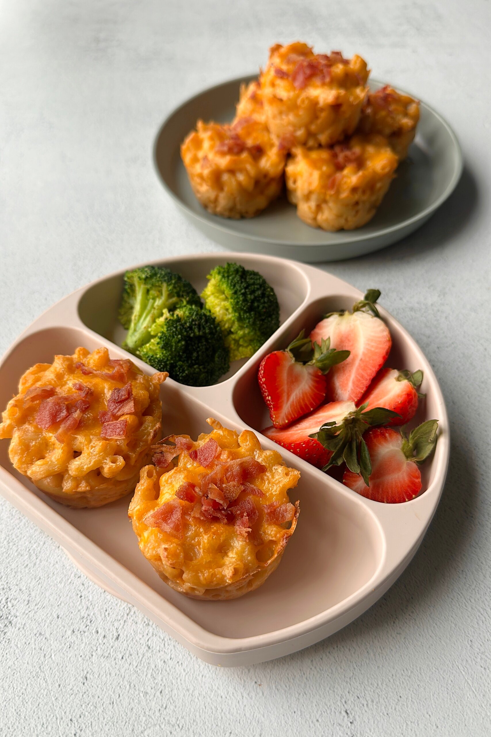 Mac and cheese muffins served with strawberries and broccoli.