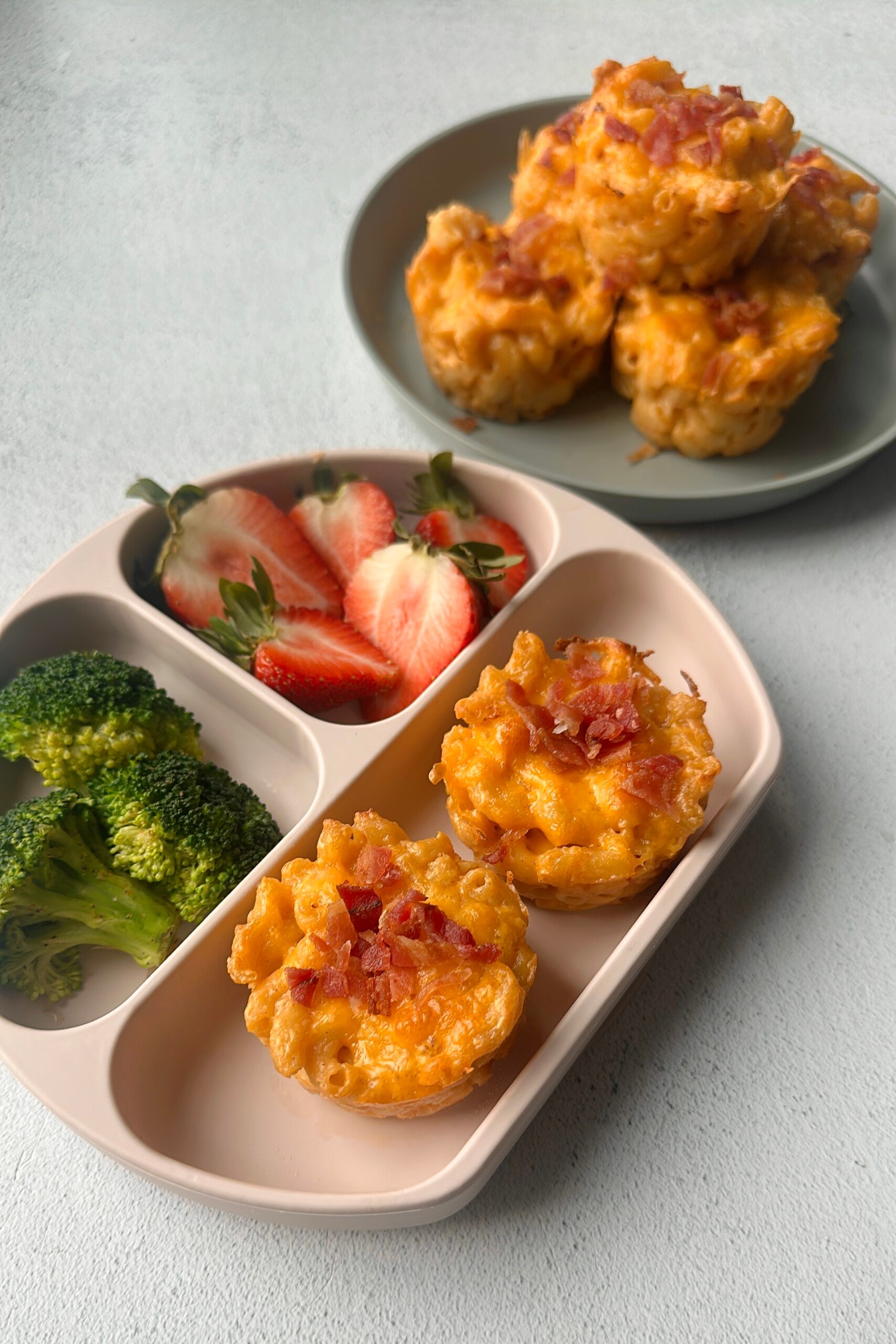 Mac and cheese muffins served with strawberries and broccoli.