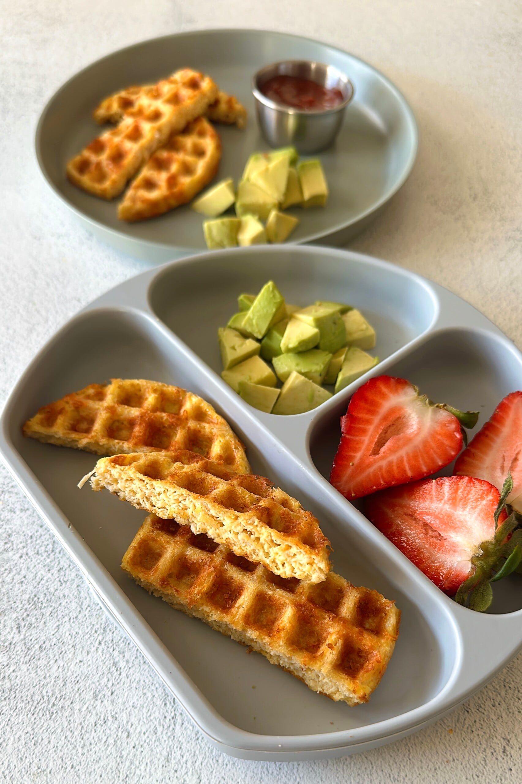 3 ingredient chicken waffles served with ketchup, avocado chunks, and strawberries.
