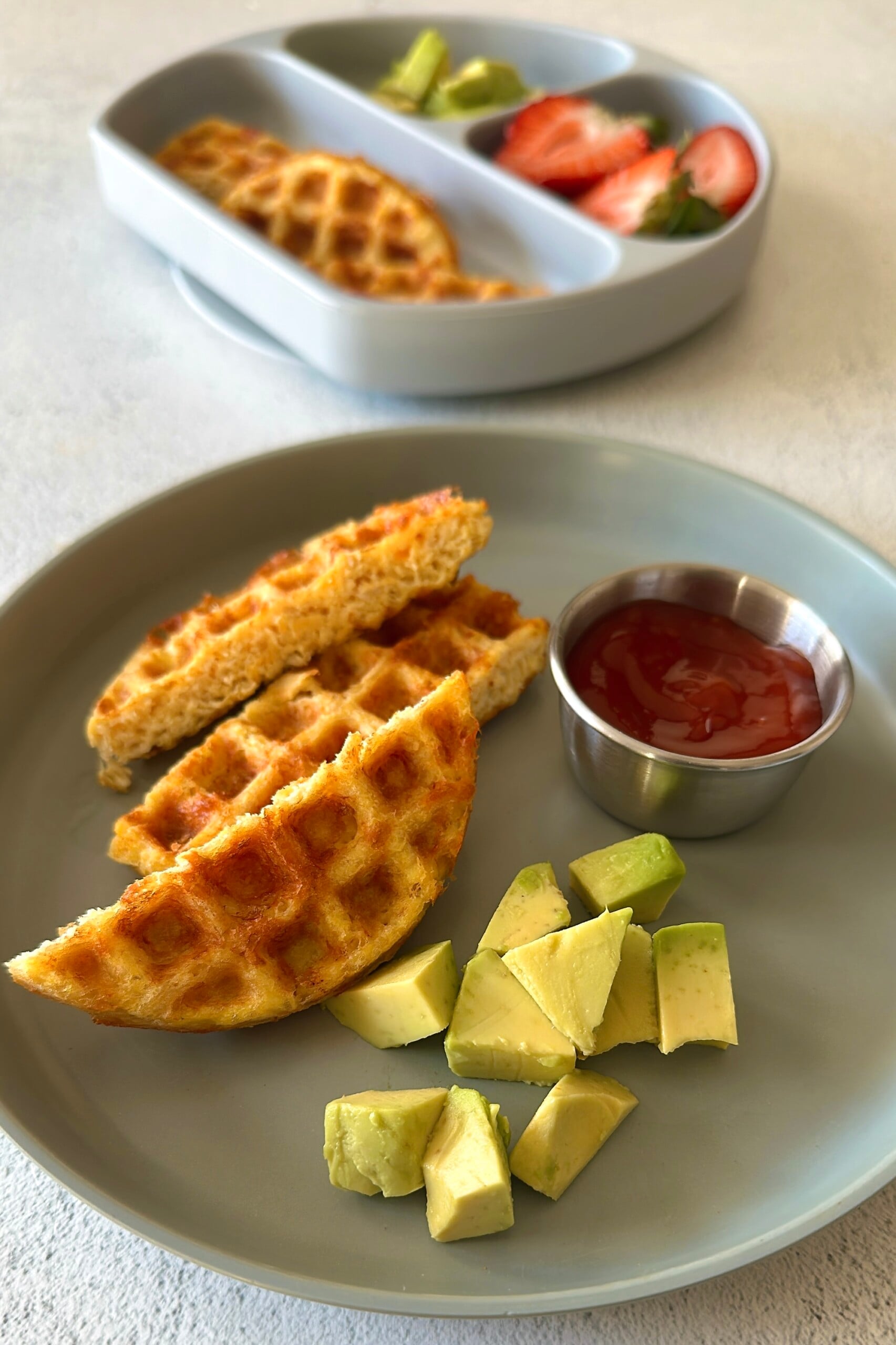 3 ingredient chicken waffles served with ketchup, avocado chunks, and strawberries.