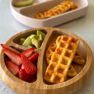3 ingredient chicken waffles served with ketchup, avocado chunks, and strawberries.