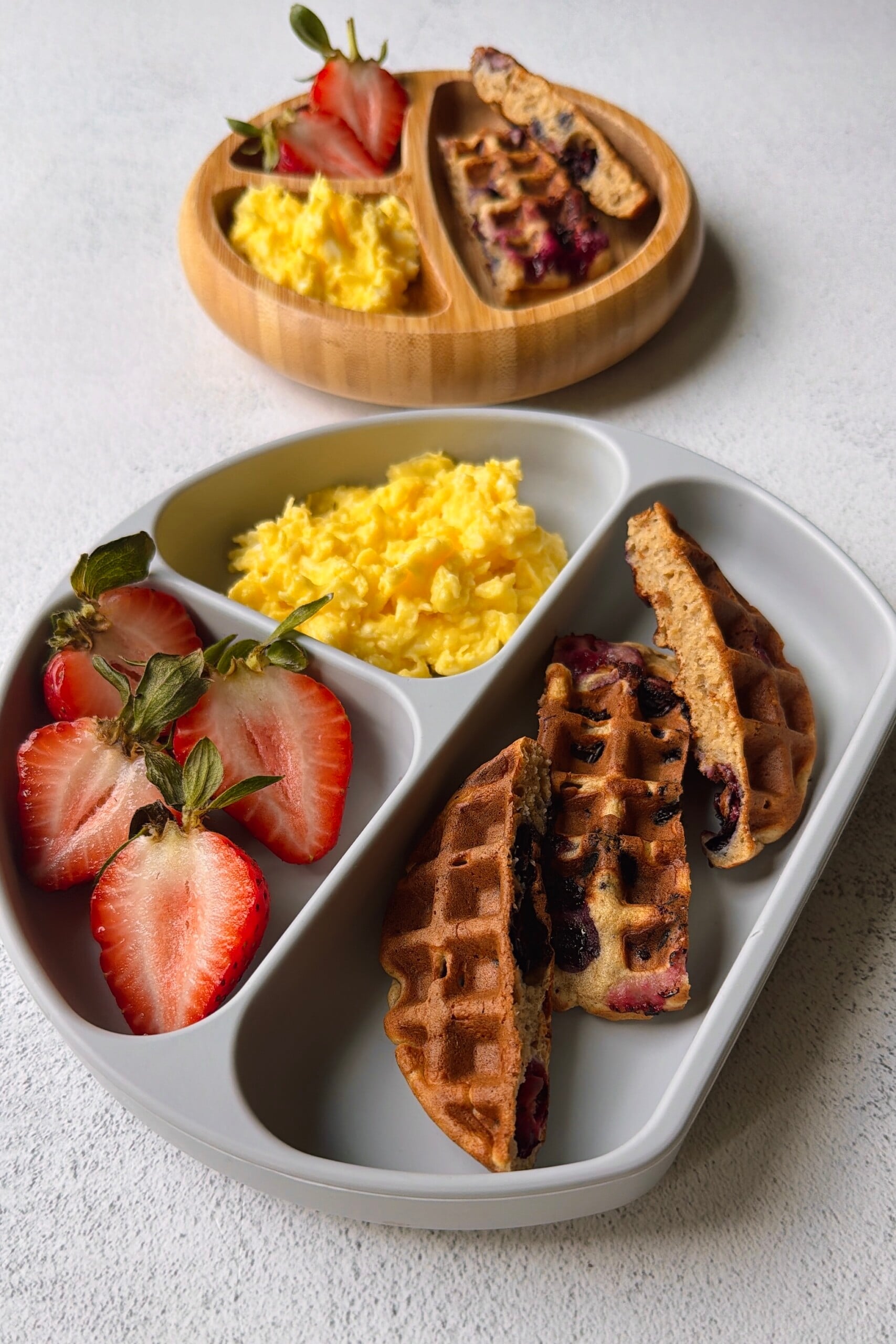 Blueberry banana waffles served with strawberries and scrambled eggs.