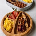 Blueberry banana waffles served with strawberries and scrambled eggs.