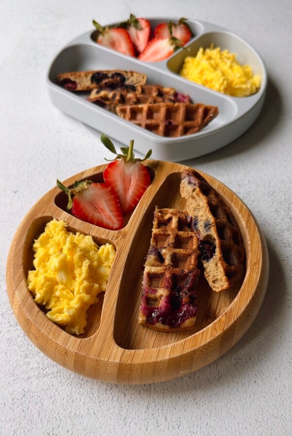Blueberry banana waffles served with strawberries and scrambled eggs.