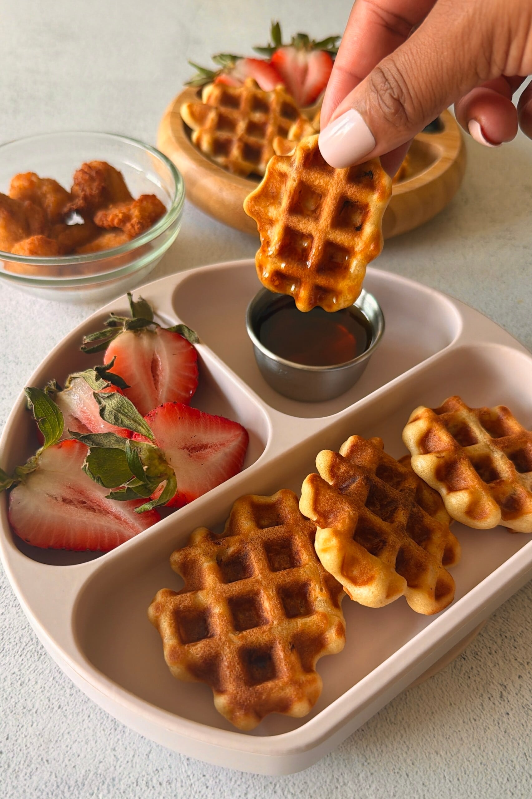 Chicken waffle bites served with berries and maple syrup.