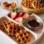 Chicken waffle bites served with berries and maple syrup.