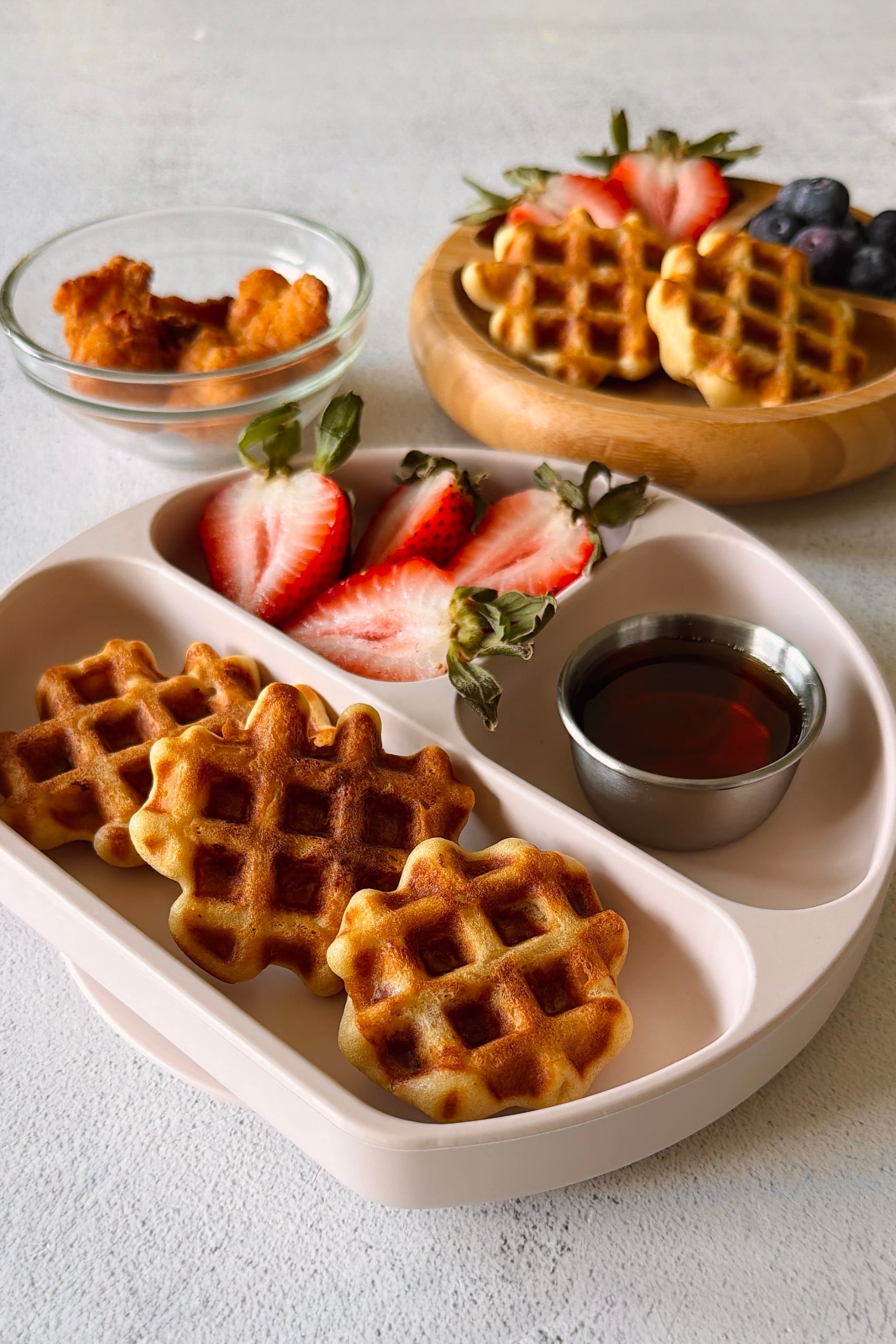 Chicken waffle bites served with berries and maple syrup.