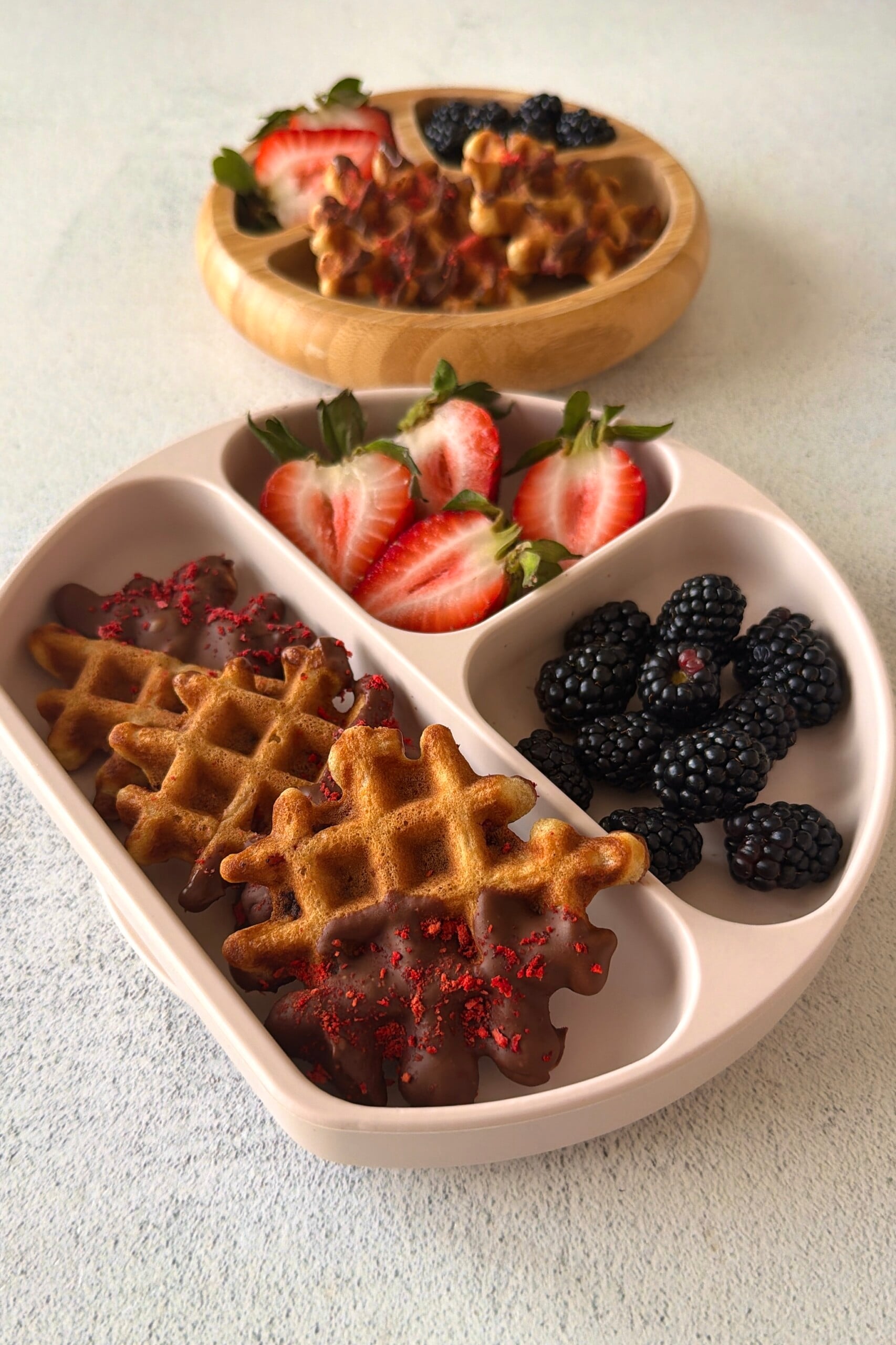 Chocolate strawberry waffles served on a plate with berries.