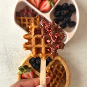 Chocolate strawberry waffles served on a plate with berries.
