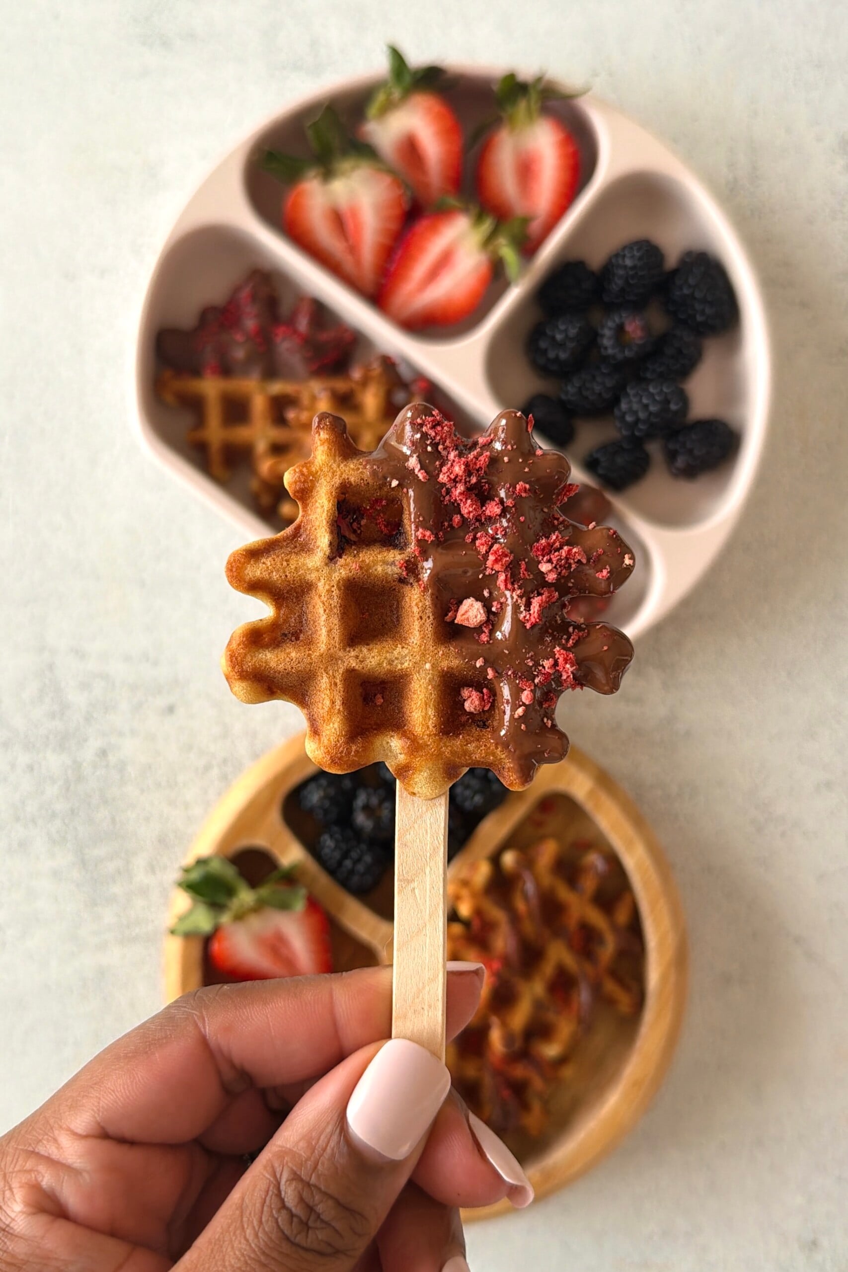 Chocolate strawberry waffles served on a plate with berries.