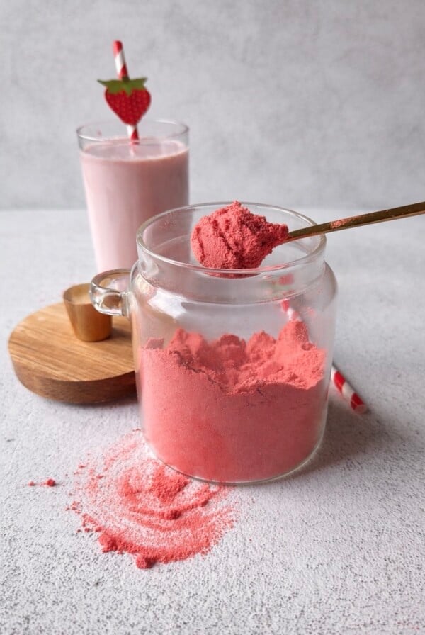Strawberry milk powder with a glass of strawberry milk.