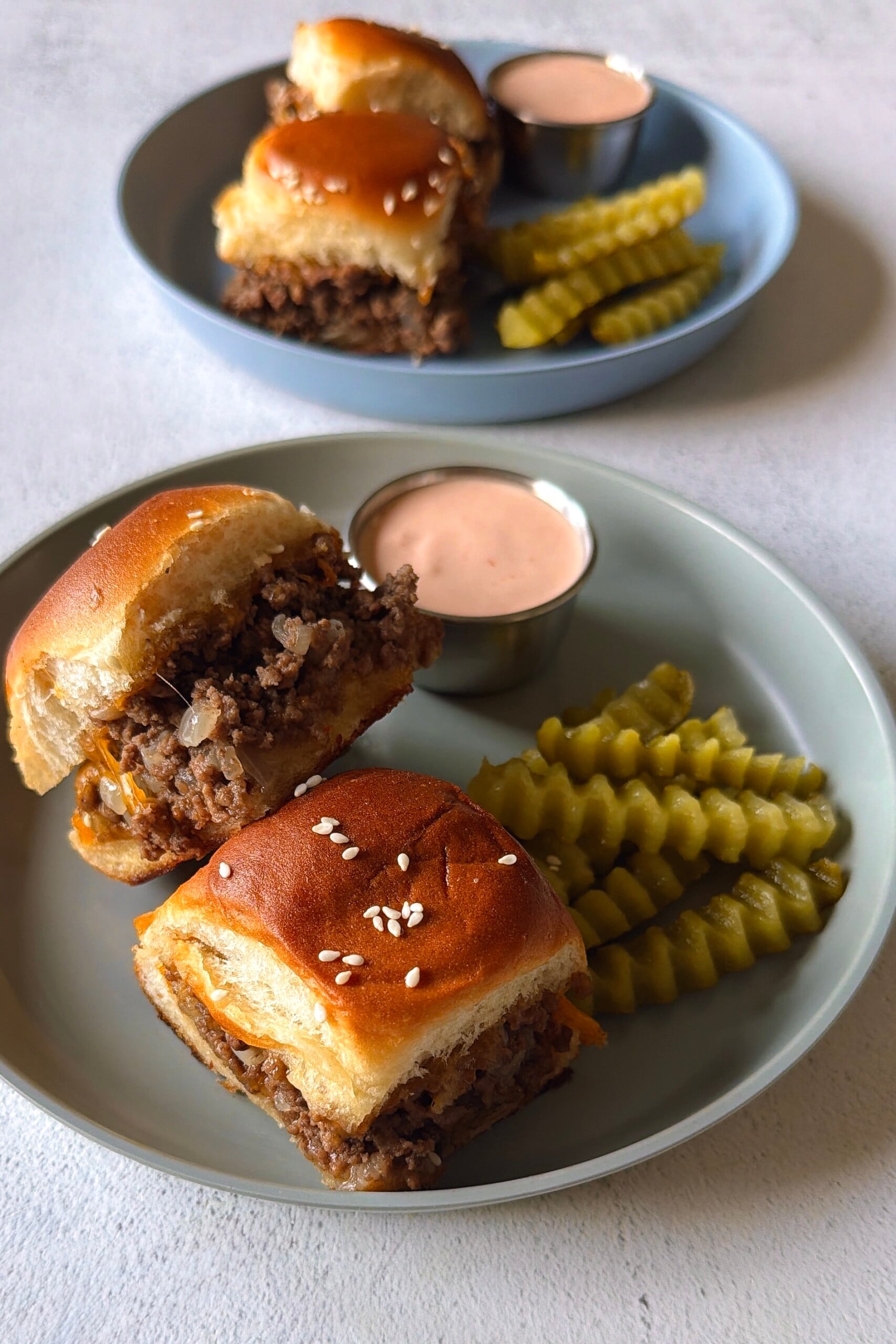 Cheeseburger sliders served with pickles and a burger sauce.
