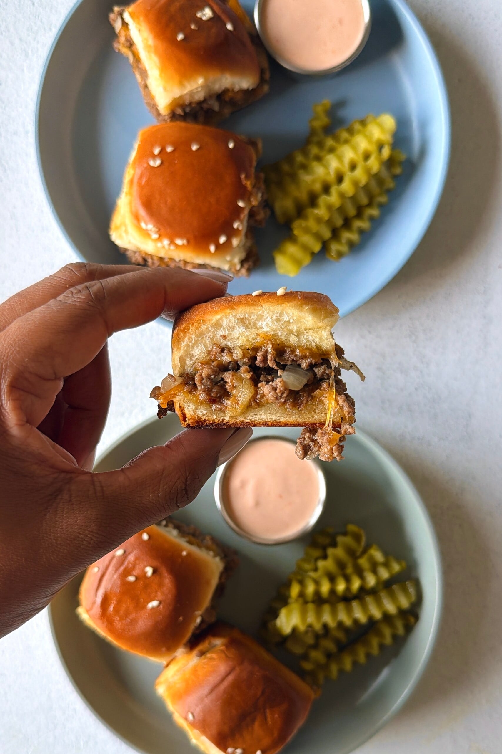 Cheeseburger sliders served with pickles and a burger sauce.