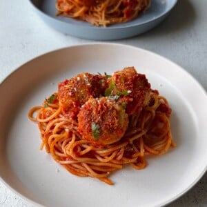 Chicken parm meatballs served with spaghetti.