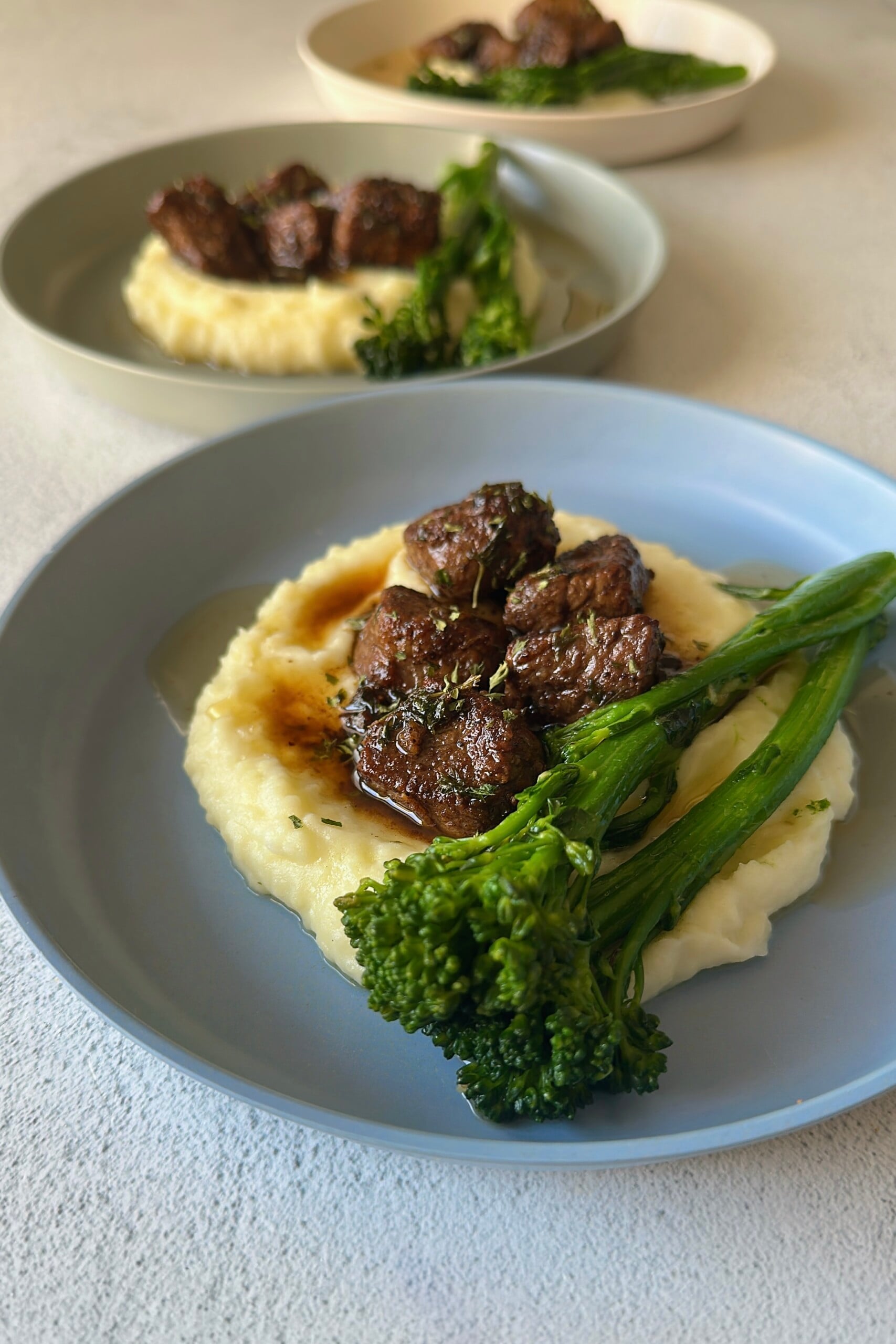 Garlic butter steak bites served with mashed potatoes and broccolini.