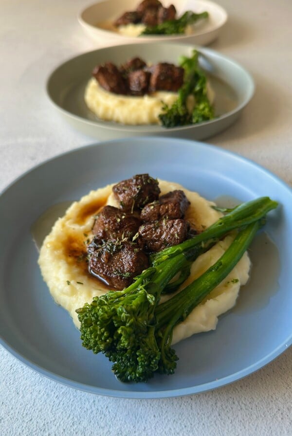 Garlic butter steak bites served with mashed potatoes and broccolini.