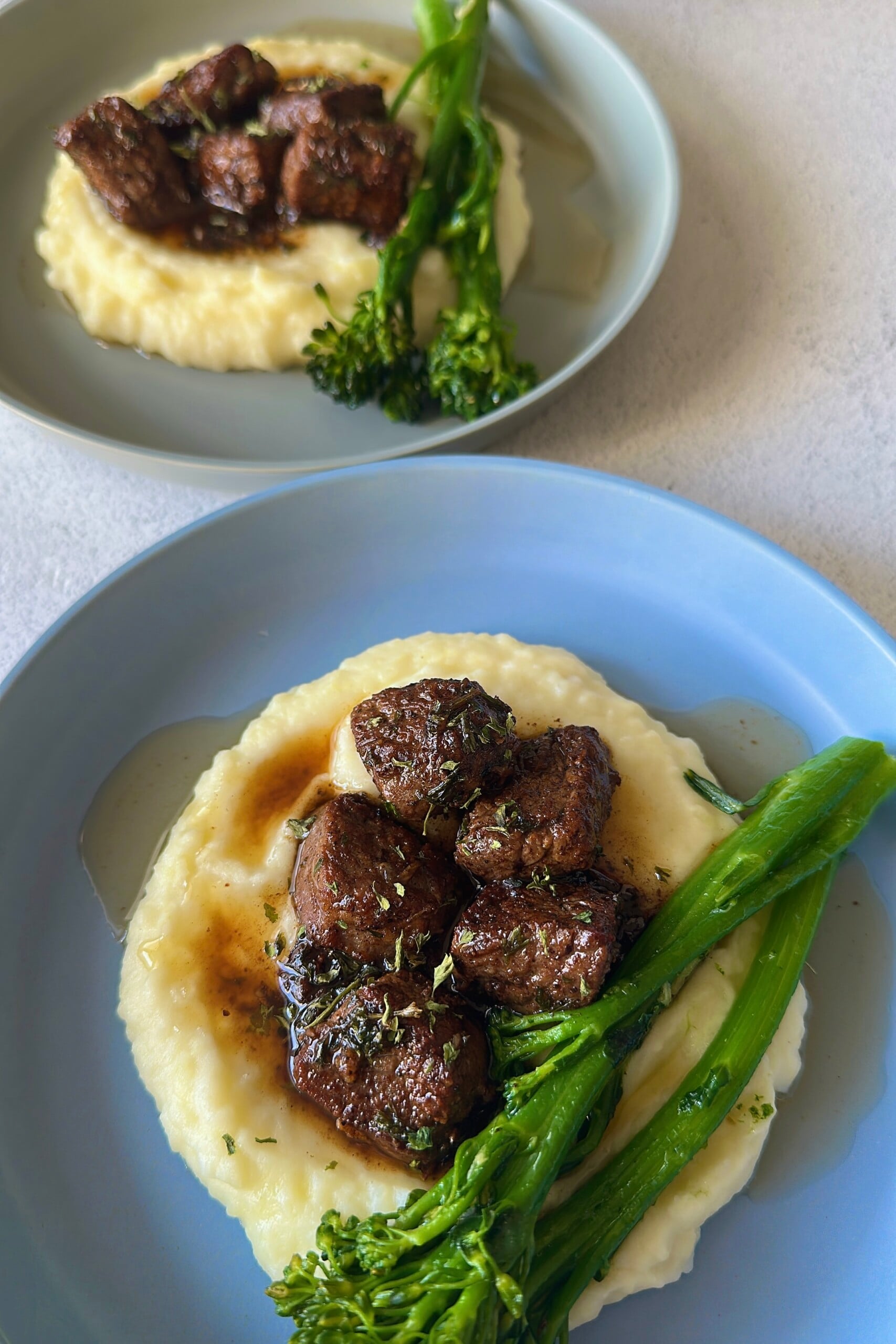 Garlic butter steak bites served with mashed potatoes and broccolini.
