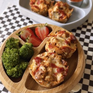Pizza cups served with pizza sauce for dipping, strawberries, and broccoli.