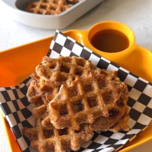 Banana waffle bites served with strawberries, yogurt, and a sauce for dipping.