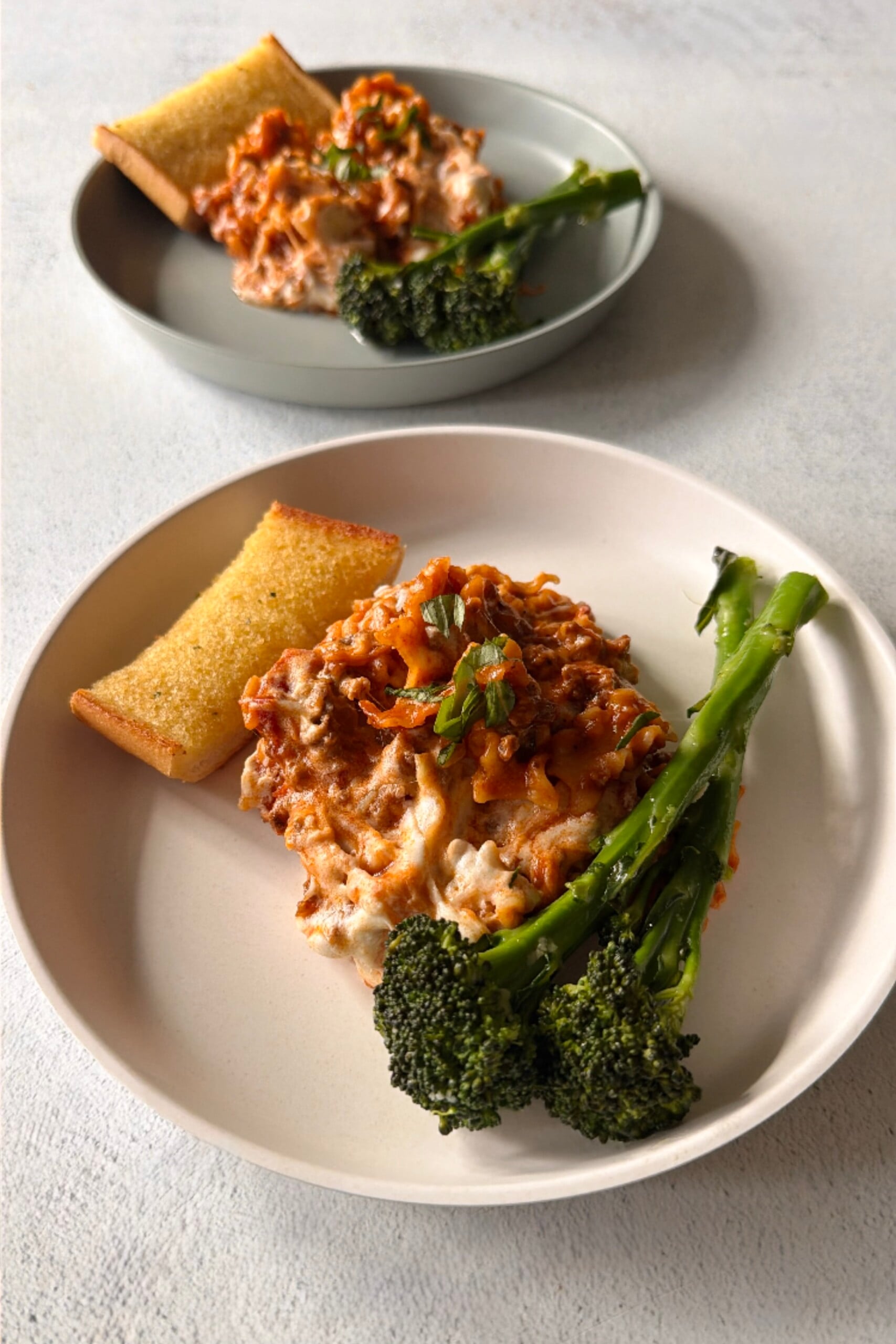 Skillet lasagna served with broccolini and garlic bread.