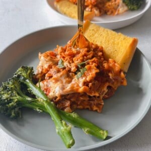 Skillet lasagna served with broccolini and garlic bread.