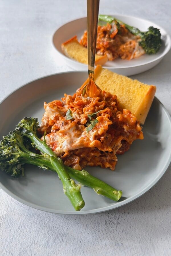 Skillet lasagna served with broccolini and garlic bread.