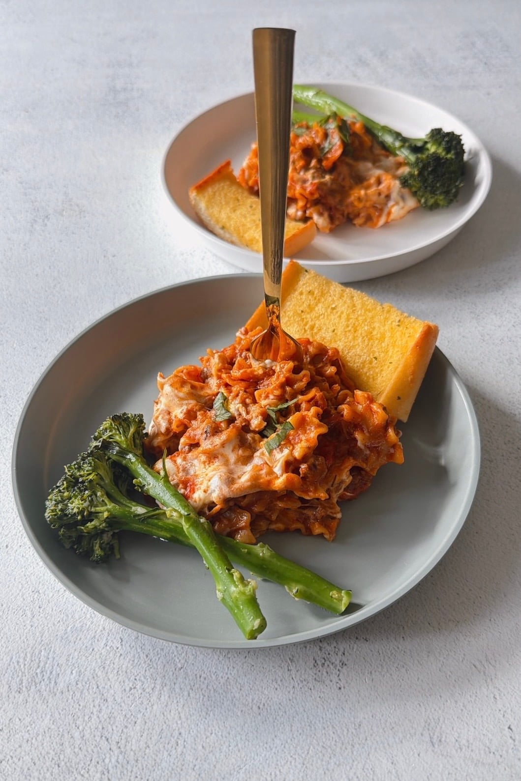 Skillet lasagna served with broccolini and garlic bread.