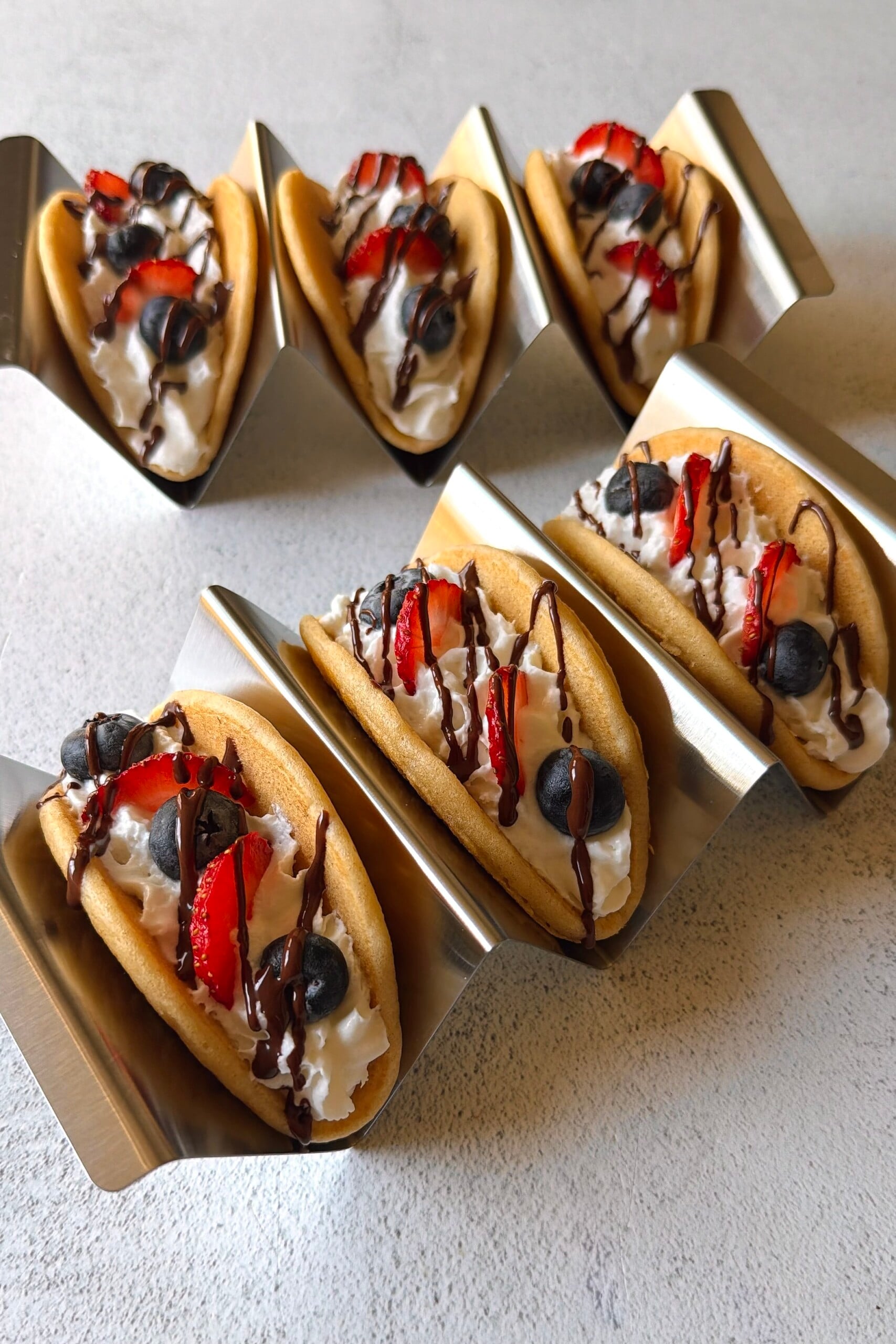 Pancake tacos served with whipped cream, berries and a chocolate drizzle.