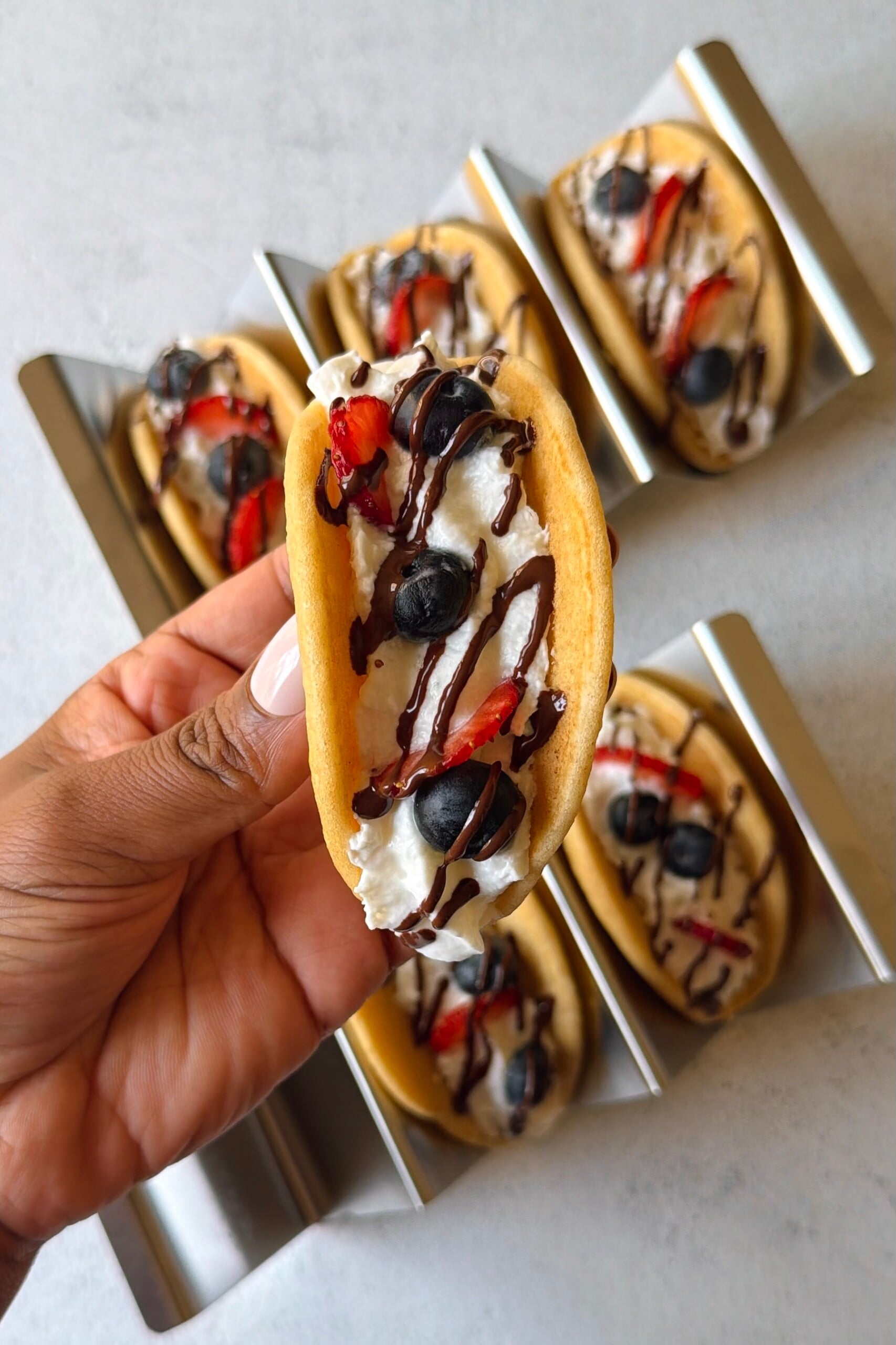 Pancake tacos served with whipped cream, berries and a chocolate drizzle.