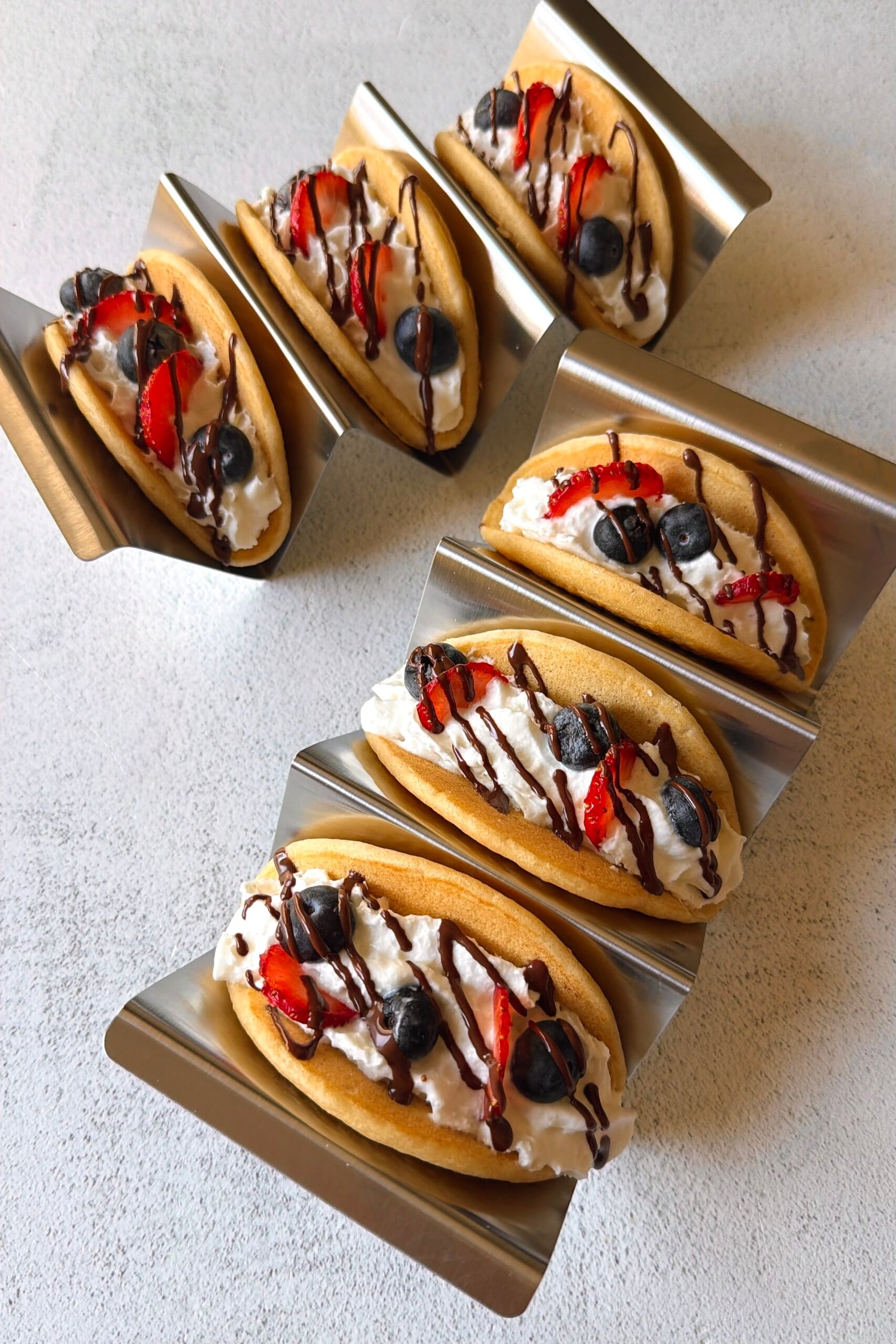 Pancake tacos served with whipped cream, berries and a chocolate drizzle.